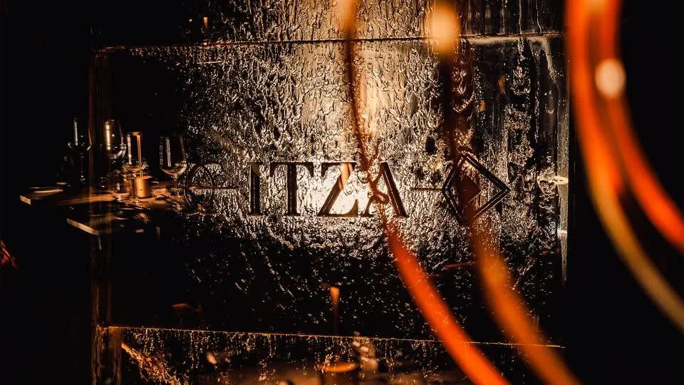 L’enseigne ITZA gravée dans un mur sombre, éclairé par des traînées de lumière