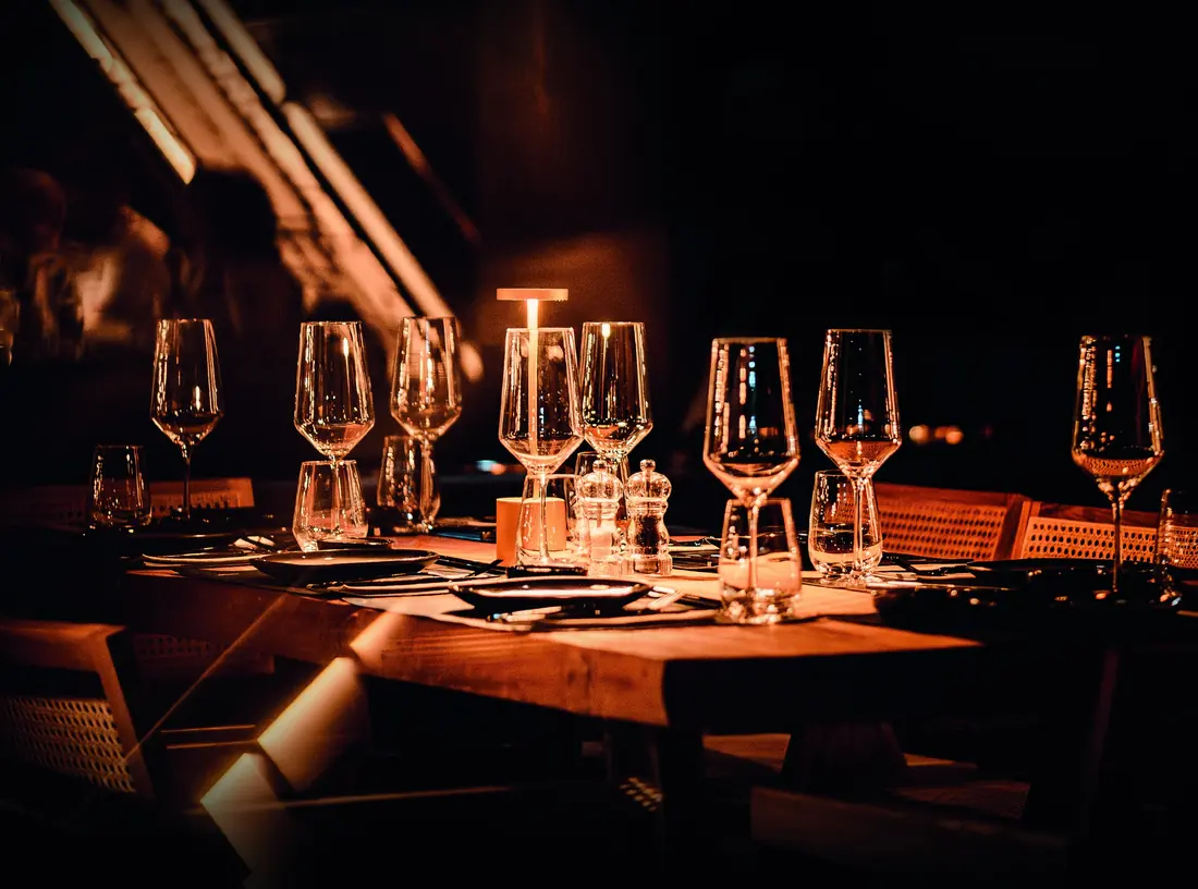 Une table dressée, verres alignés dans la pénombre